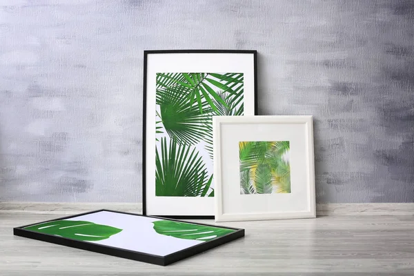 Картины в рамке тропических листьев на фоне серой стены — стоковое фото