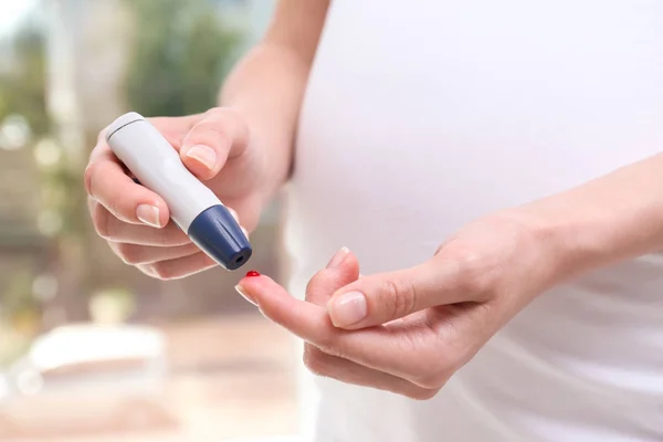 Pregnant woman taking blood sample with lancet pen — Stock Photo, Image