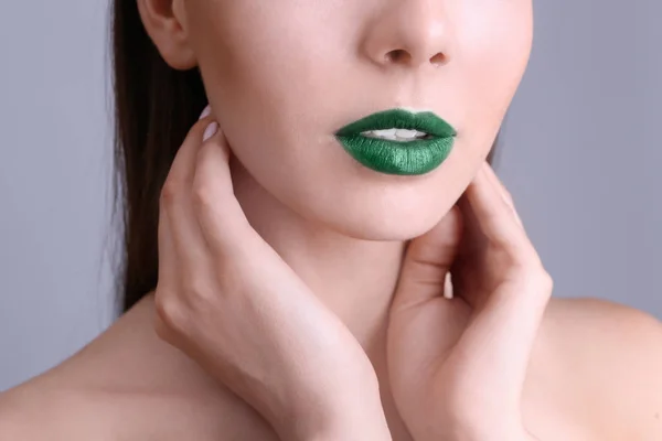 Mooie jongedame met mooie groene lippenstift op kleur achtergrond, close-up — Stockfoto