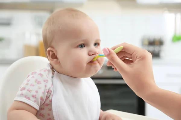 Madre alimentar al bebé con cuchara en la cocina — Foto de Stock