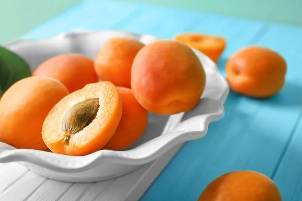 Plate with fresh apricots on wooden board — Stock Photo, Image