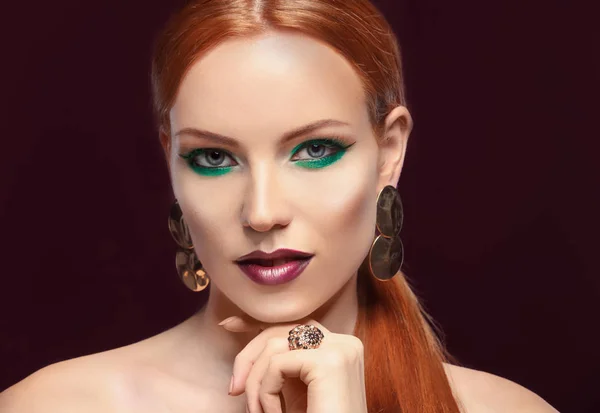 Mujer pelirroja hermosa con maquillaje verde brillante sobre fondo oscuro — Foto de Stock