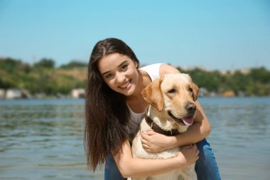 Genç kadın Nehri yakınında sarı av köpeği ile dinlenme