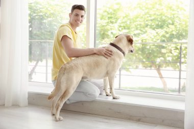 Pencere yakınındaki sarı av köpeği ile oturan genç adam