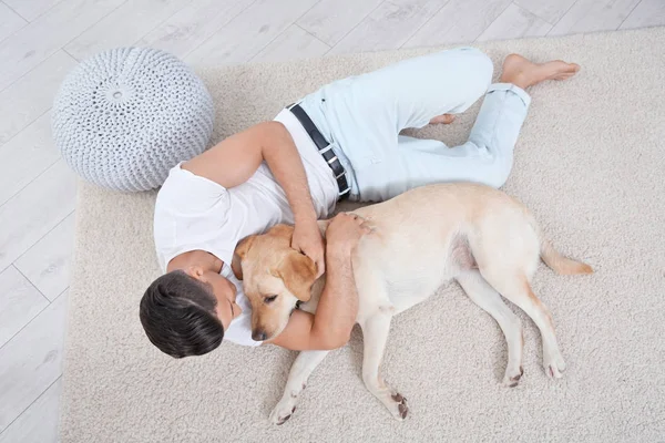 Joven descansando con amarillo retriever en casa — Foto de Stock