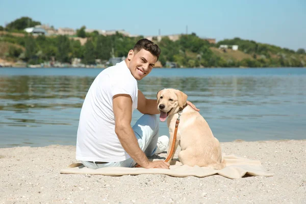 Joven descansando con amarillo retriever cerca del río — Foto de Stock