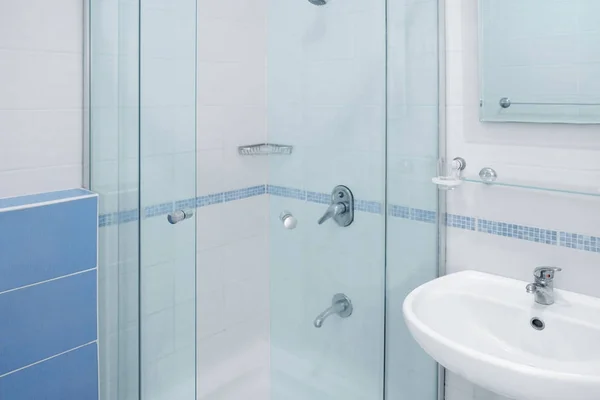 Cabine de chuveiro de vidro e pia de cerâmica branca no banheiro — Fotografia de Stock