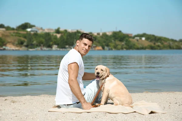 Joven descansando con amarillo retriever cerca del río — Foto de Stock