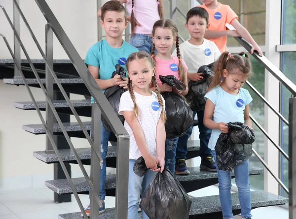 행복 한 자원 봉사자와 계단에 서 있는 쓰레기 봉투를 가진 아이 들 — 스톡 사진