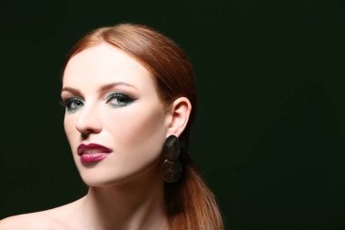 Güzel kızıl saçlı kadın koyu arka plan üzerinde parlak yeşil makyaj ile