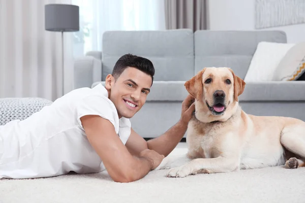 Joven descansando con amarillo retriever en casa — Foto de Stock