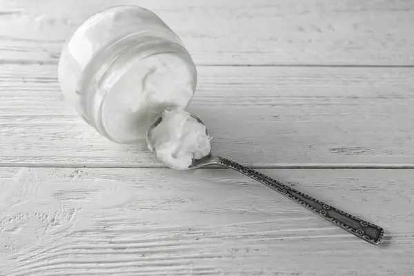 Spoon and jar with coconut oil — Stock Photo, Image