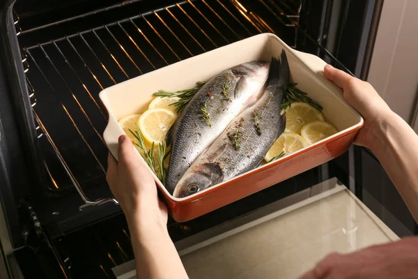 Жінка кладе піднос для випічки з рибою — стокове фото