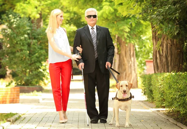 Молода жінка і сліпий чоловік з собакою-поводирем у місті — стокове фото