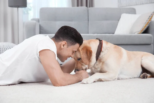 Jongeman rusten met gele retriever thuis — Stockfoto