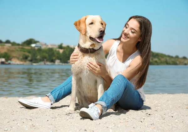 Wanita muda beristirahat dengan retriever kuning dekat sungai — Stok Foto