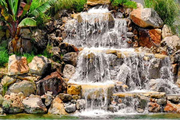 Rocks with artificial waterfall on the territory of hotel at resort — Stock Photo, Image