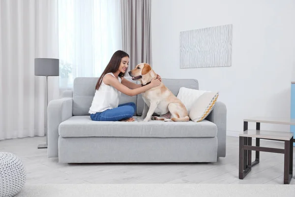 Mujer joven descansando con amarillo retriever en casa — Foto de Stock