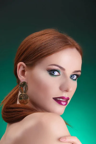 Όμορφη κοκκινομάλλα γυναίκα με έντονο πράσινο μακιγιάζ σε πράσινο φόντο — Φωτογραφία Αρχείου