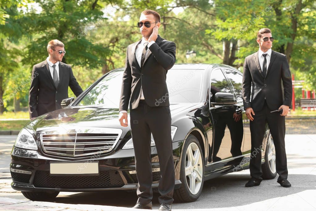 Handsome bodyguards near car  