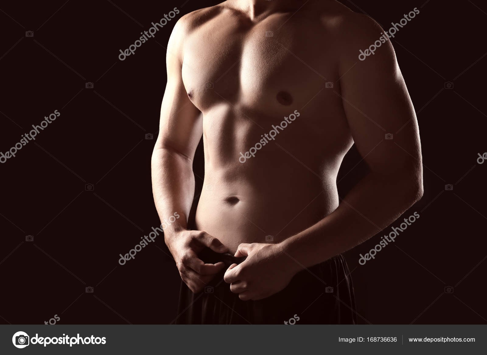 Female hands touching body of sporty young man on dark background