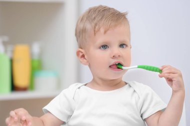 Adorable little boy brushing teeth at home clipart