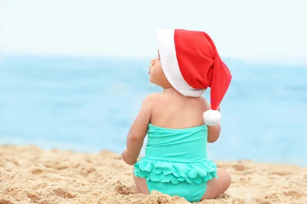 Menina adorável em chapéu de Natal na praia — Fotografia de Stock