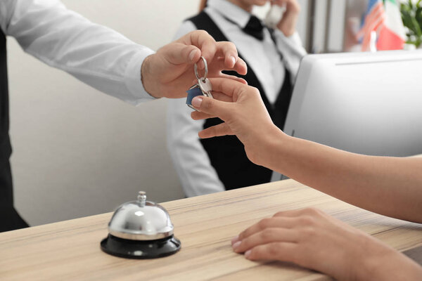 Male receptionist handing room key to woman in hotel