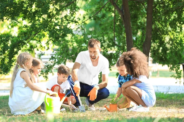 Grupa dzieci z nauczycielem sadzenia drzewko w parku — Zdjęcie stockowe