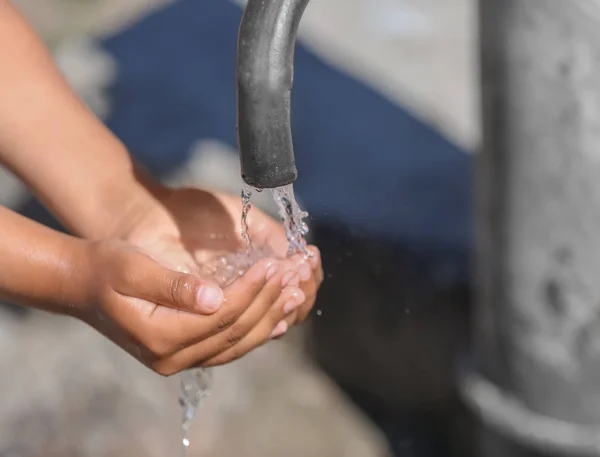 Niño afroamericano bebiendo agua del grifo al aire libre. Concepto de escasez de agua — Foto de Stock