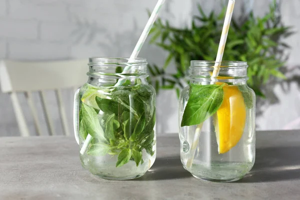 Jars with basil water on table — Stock Photo, Image