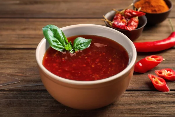 Ceramic bowl with chili sauce on wooden background — Stock Photo, Image