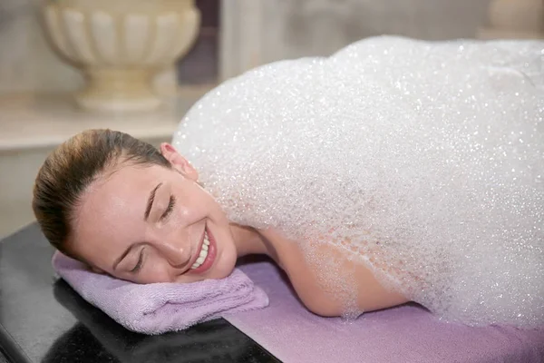 Mujer joven cubierta de espuma en hammam — Foto de Stock