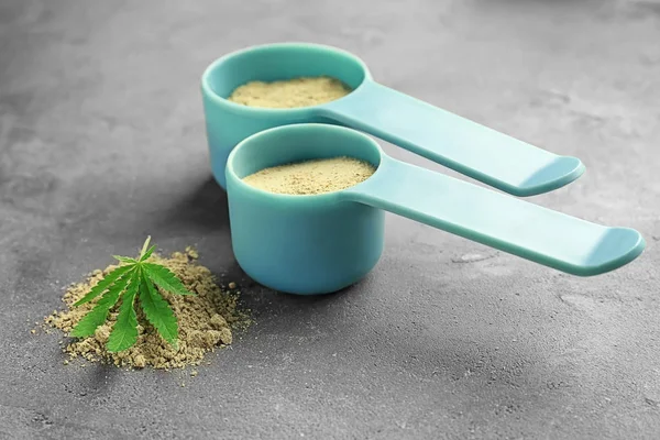 Composition with scoops of hemp protein powder on table — Stock Photo, Image