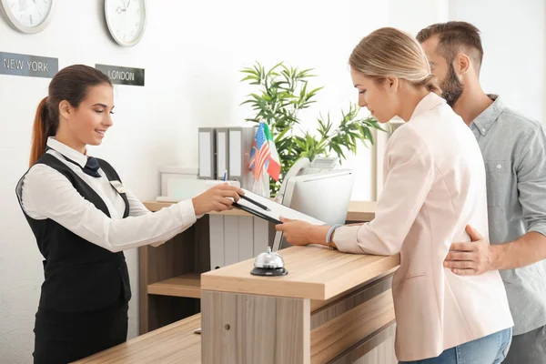 Recepcionista feminina e jovem casal no hotel — Fotografia de Stock