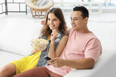 Evde televizyon izleyen genç bir çift.