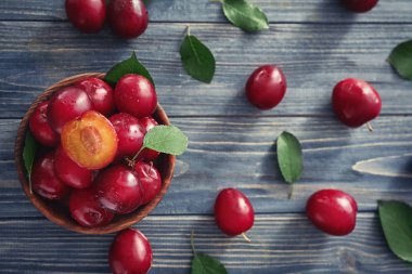 Ahşap masa üzerinde olgunlaşmış taze Erik ile kase