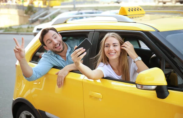 Pareja joven tomando selfie mientras está sentado en el coche de taxi —  Fotos de Stock