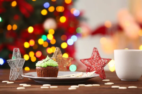 Placa con delicioso cupcake en la mesa sobre fondo borroso. Concepto de Navidad — Foto de Stock