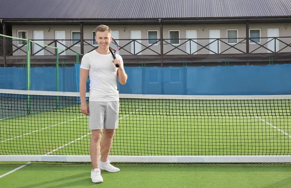 Joven con raqueta de tenis de pie en la cancha — Foto de Stock