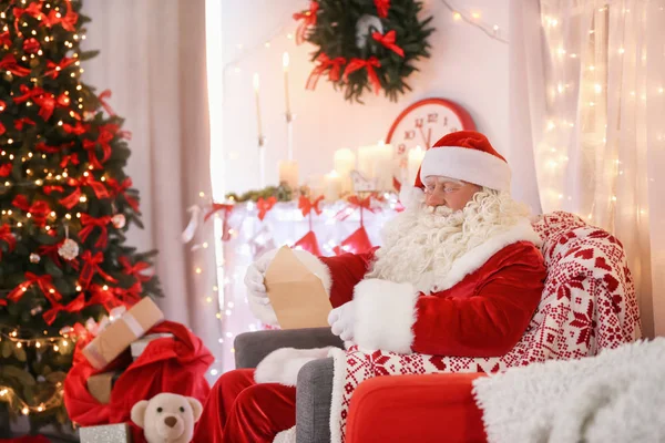 Papai Noel autêntico com carta sentada em poltrona no quarto decorado para o Natal — Fotografia de Stock