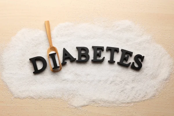 Composition with word Diabetes, sugar and wooden scoop on light background — Stock Photo, Image