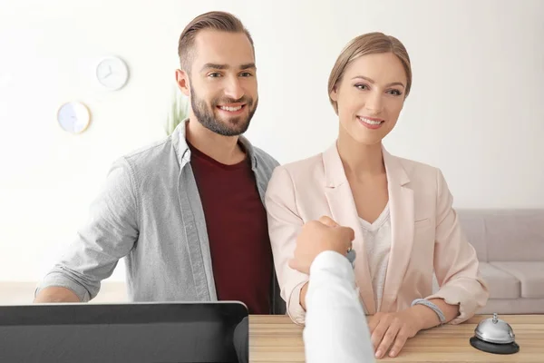 Jong koppel ontvangen sleutel van hotelkamer bij receptie — Stockfoto