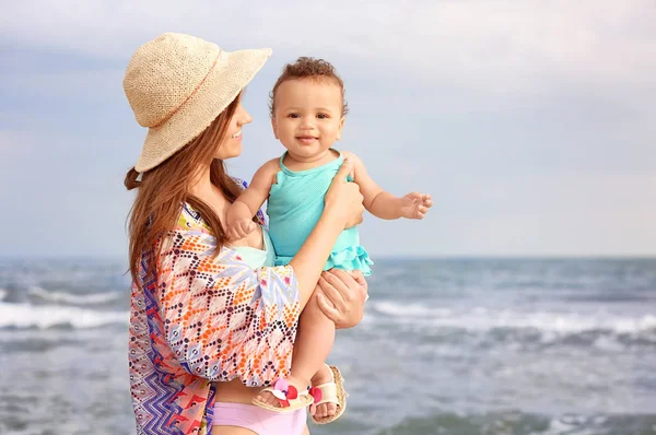 Lycklig mamma med lilla dotter på stranden — Stockfoto