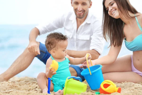 Lyckliga par med lilla dotter på stranden — Stockfoto