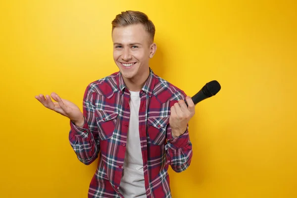 Young presenter with microphone on color background — Stock Photo, Image