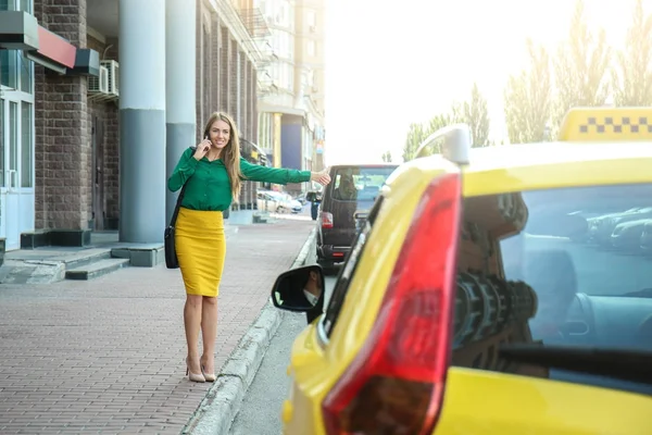 Mladá krásná žena chytání taxi na ulici — Stock fotografie