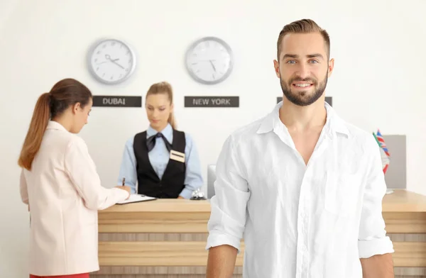 Jonge man in de buurt van de receptie balie in hotel — Stockfoto