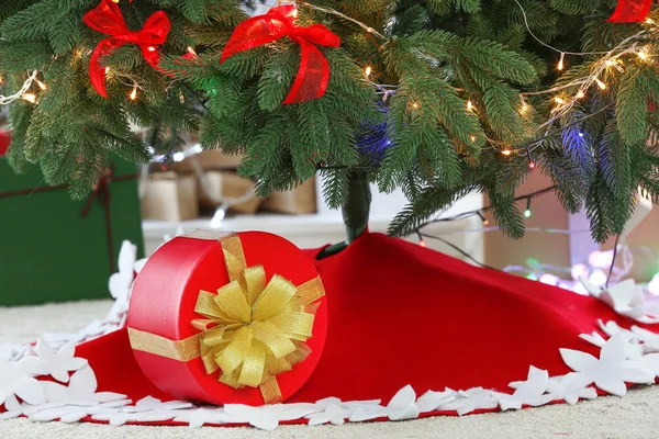 Beautiful Christmas tree with skirt and gift box in room — Stock Photo, Image