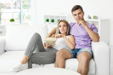 Evde televizyon izleyen genç bir çift.